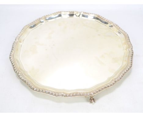 COOPER BROS &amp; SONS LTD; a George VI hallmarked silver salver of shaped circular form with gadrooned rim, on three ball an