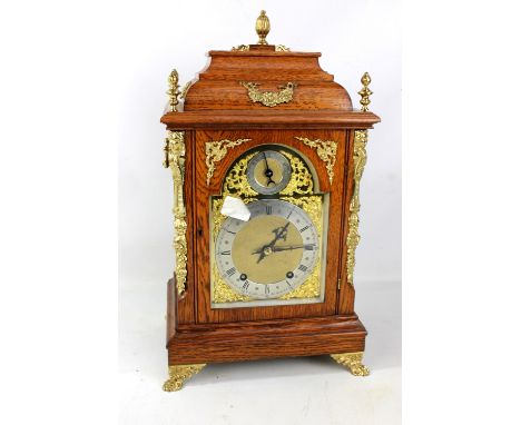 An Edwardian oak and brass mounted bracket clock, the arched brass dial set with silvered chapter ring and slow/fast subsidia