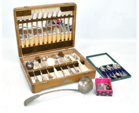 An oak canteen of various flatware, a ladle, a cased set of six enamel decorated teaspoons and a small group of variously hal
