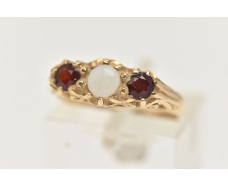 A 9CT GOLD OPAL AND PASTE RING, designed as a central circular opal cabochon flanked by circular cut red paste, to the scroll