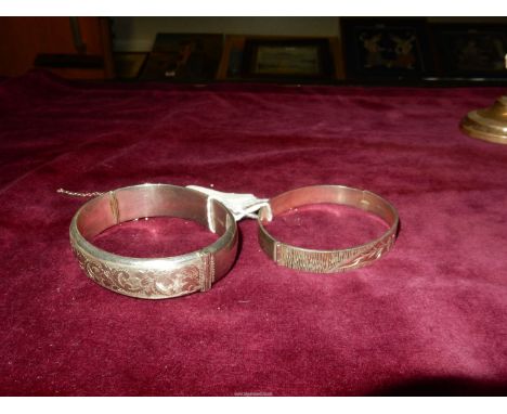 Two silver Bangles with scroll and floral designs, one with dent and safety chain broken, 49 grams total.