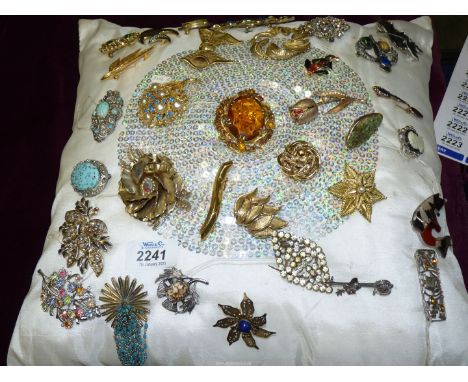 A cushion full of brooches in various styles to include; turquoise, glass, Celtic, bar brooches, etc.