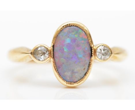 An 18ct gold black opal and diamond three stone ring, Birmingham 1914, milligrain collet set with an oval stone, 10 6mm, flan