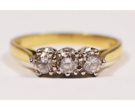 An 18ct gold three stone diamond ring, claw set with brilliant cut stones, London 1986, stated weight 0.58ct, colour estimate