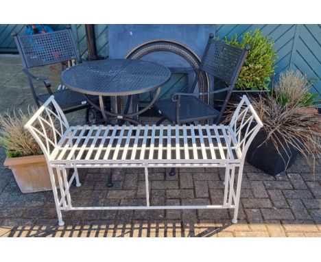 A metal garden table and two chairs, a metal bench, and flower pots 