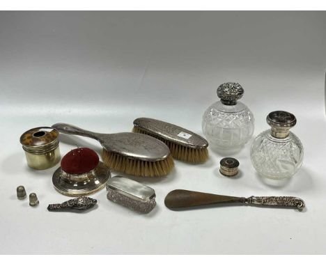 Two silver topped glass perfume bottles, a silver topped glass jar, a silver pincushion, a silver and tortoiseshell patch box