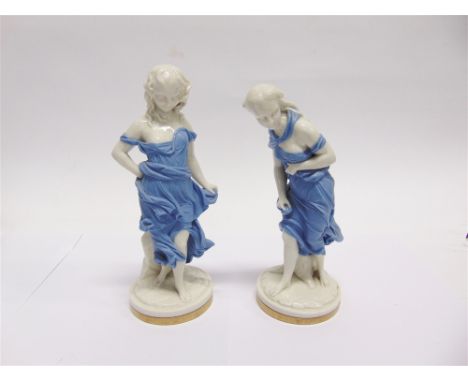 A PAIR OF ROYAL WORCESTER FIGURES:  'Before the Wind' and 'Against the Wind', each modelled as a young girl wearing a pale ma