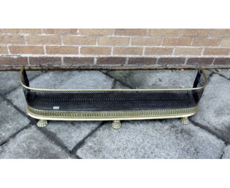 A VICTORIAN D-SHAPED PIERCED BRASS FENDER  with lions paw feet, 107cm wide