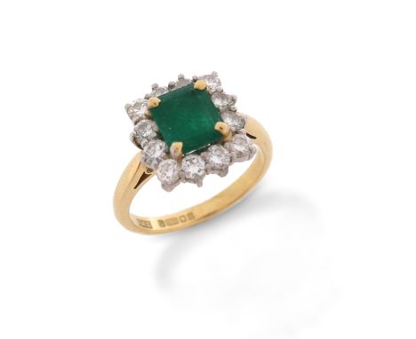 An emerald and diamond cluster ring, the emerald-cut emerald set within a surround of round brilliant-cut diamonds in 18ct ye