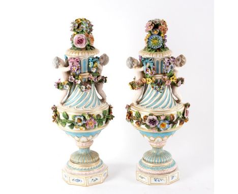 A pair of late 19th Century Continental vases and covers, set with cherubs and swags of flowers in relief and raised on octag