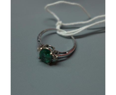 A ladies 9ct white gold ring, inset with possibly tourmaline to center flanked by two round cut diamonds 