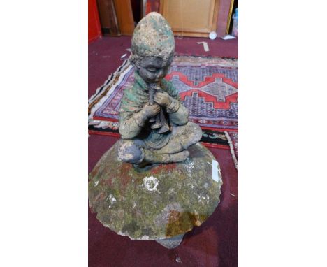 A reconstituted stone statue of a pixie playing pipes, sitting on a mushroom, H.66cm 