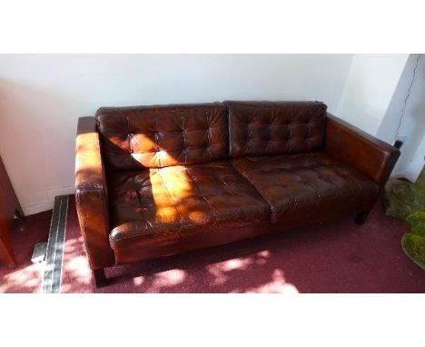 A Florence Knoll style three seater sofa, with brown leather button back upholstery, raised on ebonised legs 