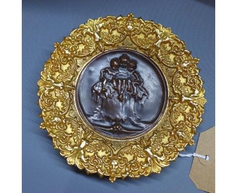 A 20th century Continental brass dish, with central bronze plaque, depicting three children sitting on a tree trunk 