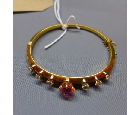 A yellow metal ladies bangle, inset with diamonds and central tourmaline which unscrews. Diamonds approx. 1cts combined