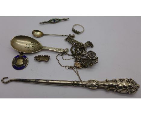 Assorted silver items including a marcasite necklet, two brooches, a caddy spoon, a button hook, a spoon and charms, 50g weig