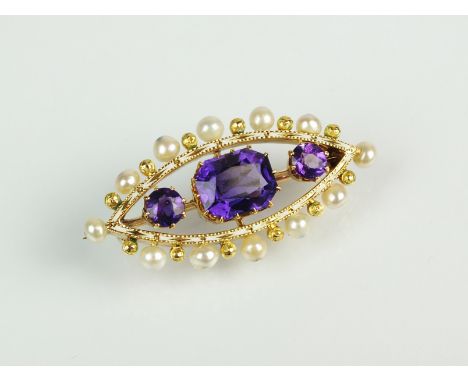An early 20th century amethyst, enamel and pearl brooch, designed as a central trap cut amethyst flanked to each side by a ro