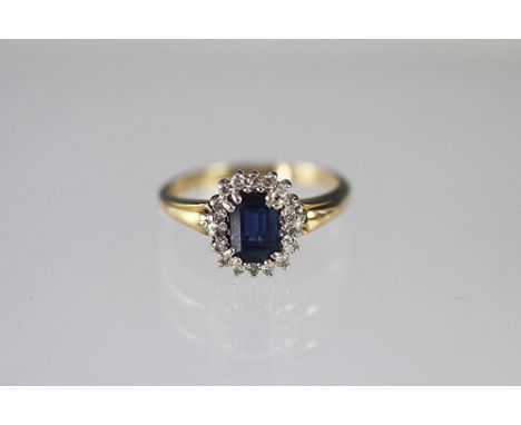 A sapphire and diamond oval cluster ring, the central sapphire within a surround of eight cut diamonds, all claw set in white