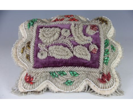 A Victorian bead work cushion, worked with a foliate motif with clear and colour glass beads against a velvet ground, 24cm x 