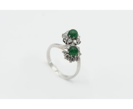 AN EMERALD AND DIAMOND RING, the cross over style mount set with two round cabochon cut emeralds with carved detailing, each 