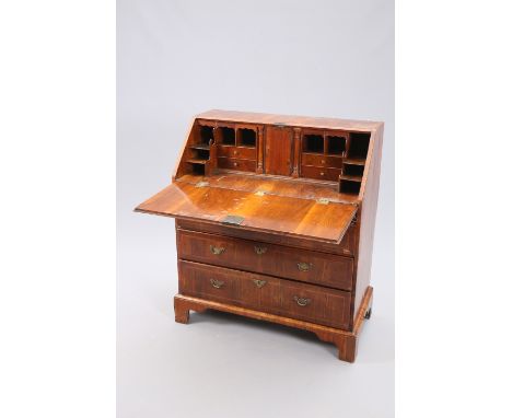 A GEORGE II FEATHER BANDED WALNUT BUREAU, the hinged slope opening to reveal a fitted interior, above four long graduated dra