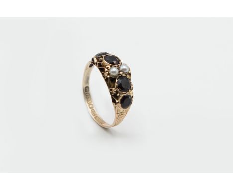A LATE GEORGIAN GARNET AND SEED PEARL RING, the four graduating round cut garnets and two seed pearls set in a delicate scrol