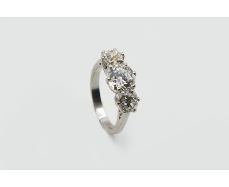 A THREE STONE DIAMOND RING, the three graduating brilliant cut claw set diamonds set in a simple pierced mount between taperi