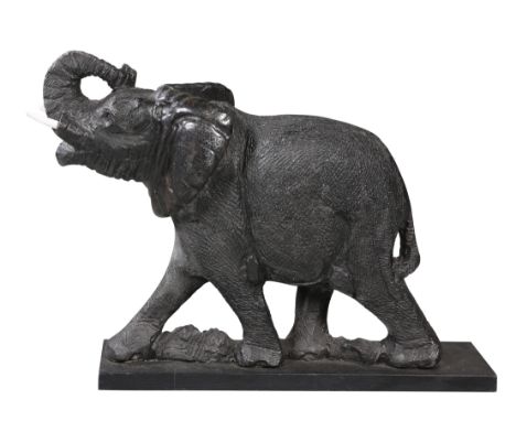 A LARGE CARVED STONE MODEL OF AN ELEPHANT, POSSIBLY INDIAN, modelled with trunk upraised, on a wooden base. Height excluding 