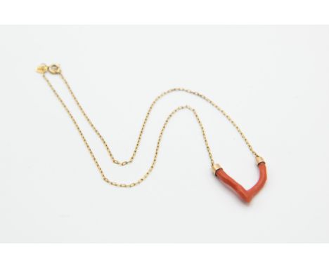 A CORAL AND GOLD PENDANT, the single coral strand formed as a wishbone, set to the bottom of a fine link yellow gold chain on