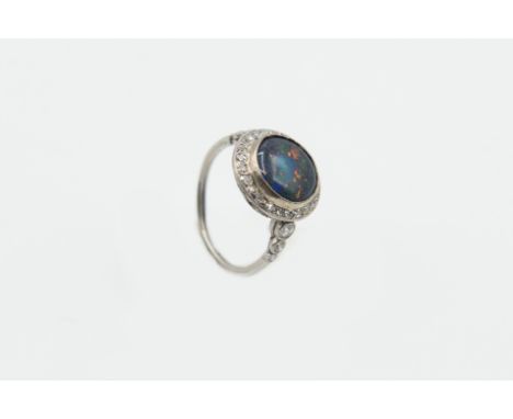 A BLACK OPAL AND DIAMOND RING, the round cut black opal set raised within a surround of old cut diamond highlights in a pierc