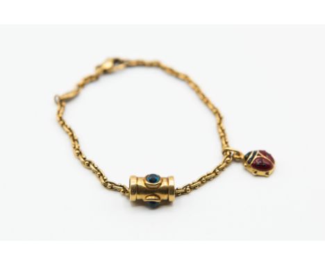 A GOLD AND ENAMEL BRACELET, the fine link chain with an articulated barrel charm with blue stone highlights and an articulate