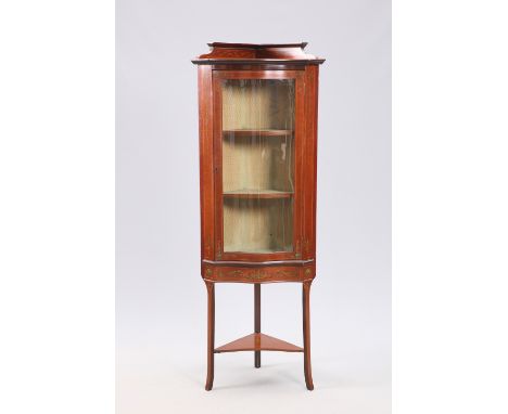 AN EDWARDIAN PAINTED MAHOGANY CORNER VITRINE, with serpentine front, the glazed door enclosing two shelves, raised on square 