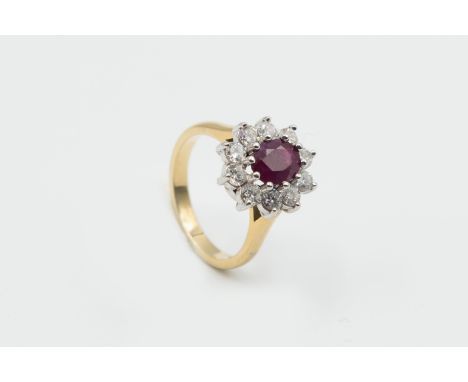 A RUBY AND DIAMOND RING, the oval cut ruby ten claw set within a surround of ten brilliant cut claw set diamonds in a pierced