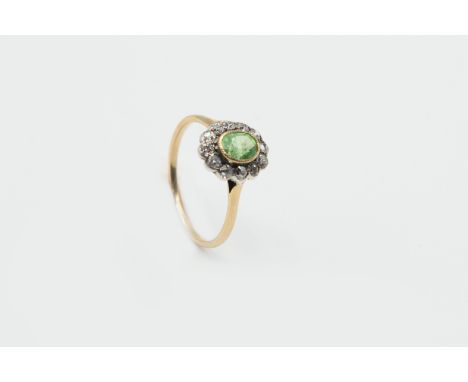 A DEMANTOID GARNET AND DIAMOND RING, circa 1880-1890, the oval cut demantoid garnet set raised within a surround of twelve ol