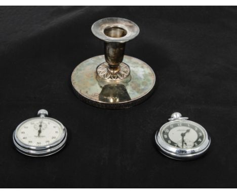 A small silver candlestick, a stop watch and one other