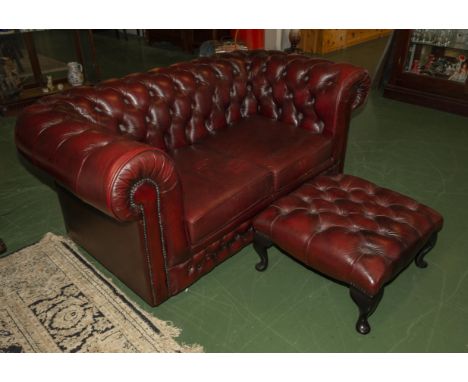 A red Chesterfield two seater sofa and foot stool