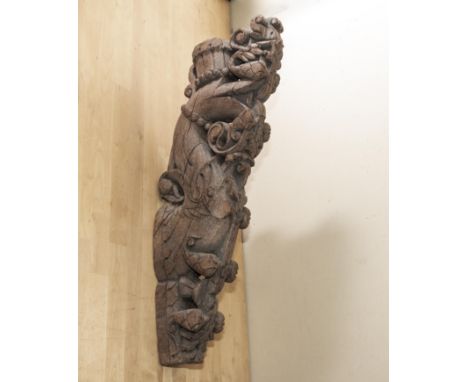 A carved Indian teak corbel bracket, late 19th early 20th century, featuring a serpents head wearing a crown, 67cm long