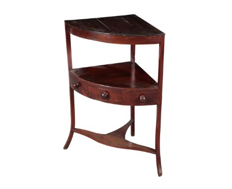 AN EARLY 19TH CENTURY MAHOGANY BOW-FRONT CORNER STAND with a single frieze drawer to the second shelf, on out turned legs, 82