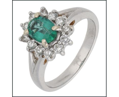 An emerald and diamond cluster ring, the oval-shaped emerald within a surround of brilliant-cut diamonds, to a plain polished