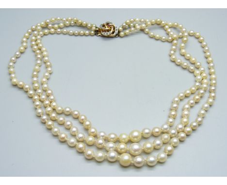 A three strand pearl necklace with a ruby and diamond clasp 