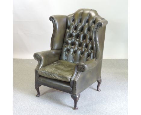 A mid 20th century green upholstered button back wing armchair 