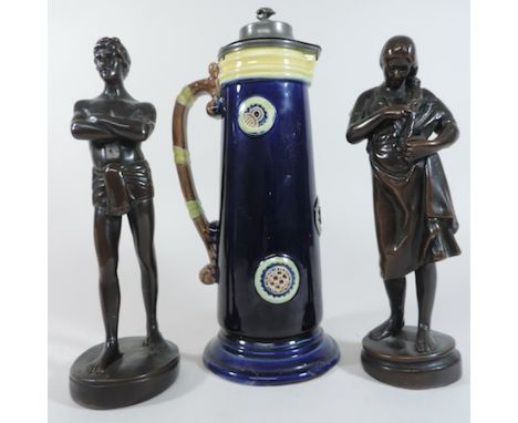 An Art Nouveau style pottery tankard, 31cm tall, together with two bronze painted figures