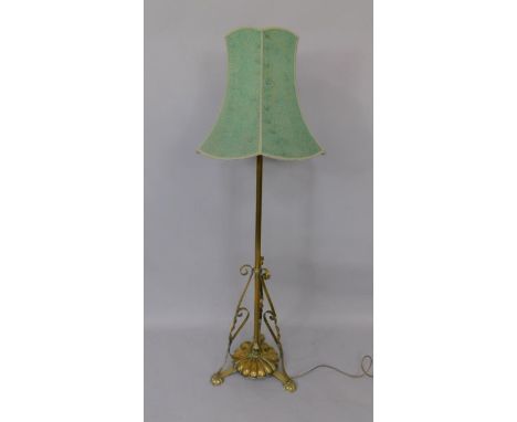 A Victorian brass standard lamp, with scrolling supports and three fluted feet, with shade, 152cm high.