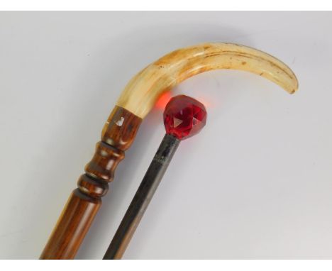 A hardwood walking stick with a warthog tusk handle, 91cm long, together with an ebonised walking stick with a faceted red gl