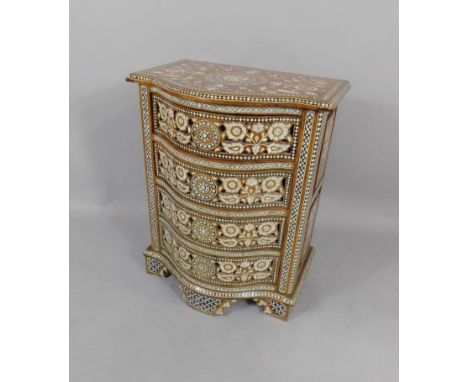A Damascene hardwood serpentine chest of drawers, with ebony and mother of pearl floral inlay, with four drawers, raised on b