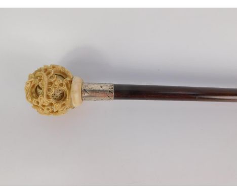 A Chinese ivory puzzle ball topped walking stick, carved externally with dragons amongst clouds, on an Edwardian rosewood sha