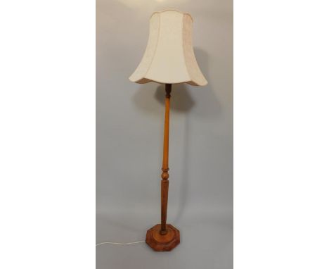 An early 20thC pale oak turned standard lamp, raised on an octagonal base, with shade, 200cm high.