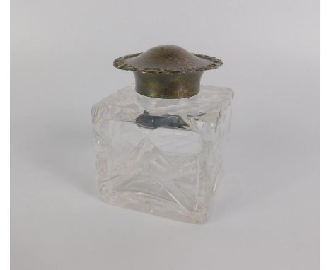 A Victorian cut glass inkwell, with a silver mount and hinged lid, with pierced and embossed floral and c scroll border decor