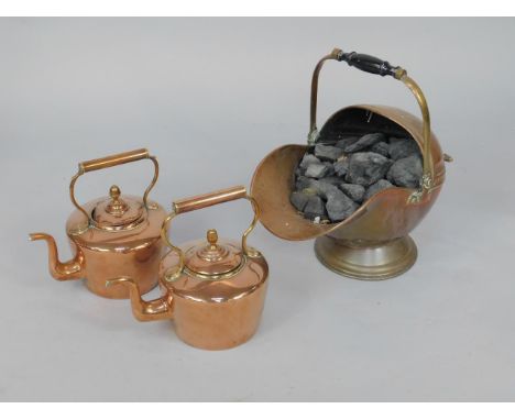 A Victorian copper helmet coal scuttle, with coal, and two copper kettles.