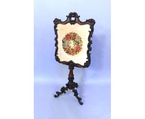 A Victorain rosewood and tapestry fire screen, with foliate carved decoration, raised on a baluster turned column and three s